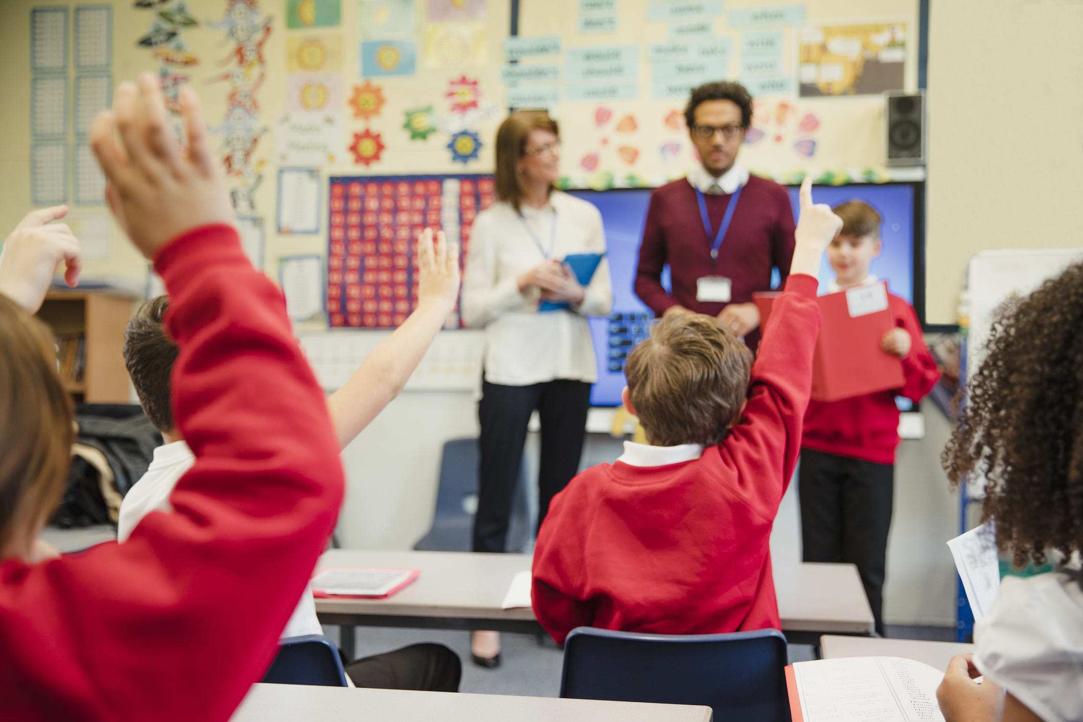 children putting their hands up in a classroom