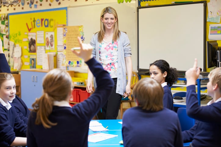 Teacher and a group of pupils in classroom asking questions