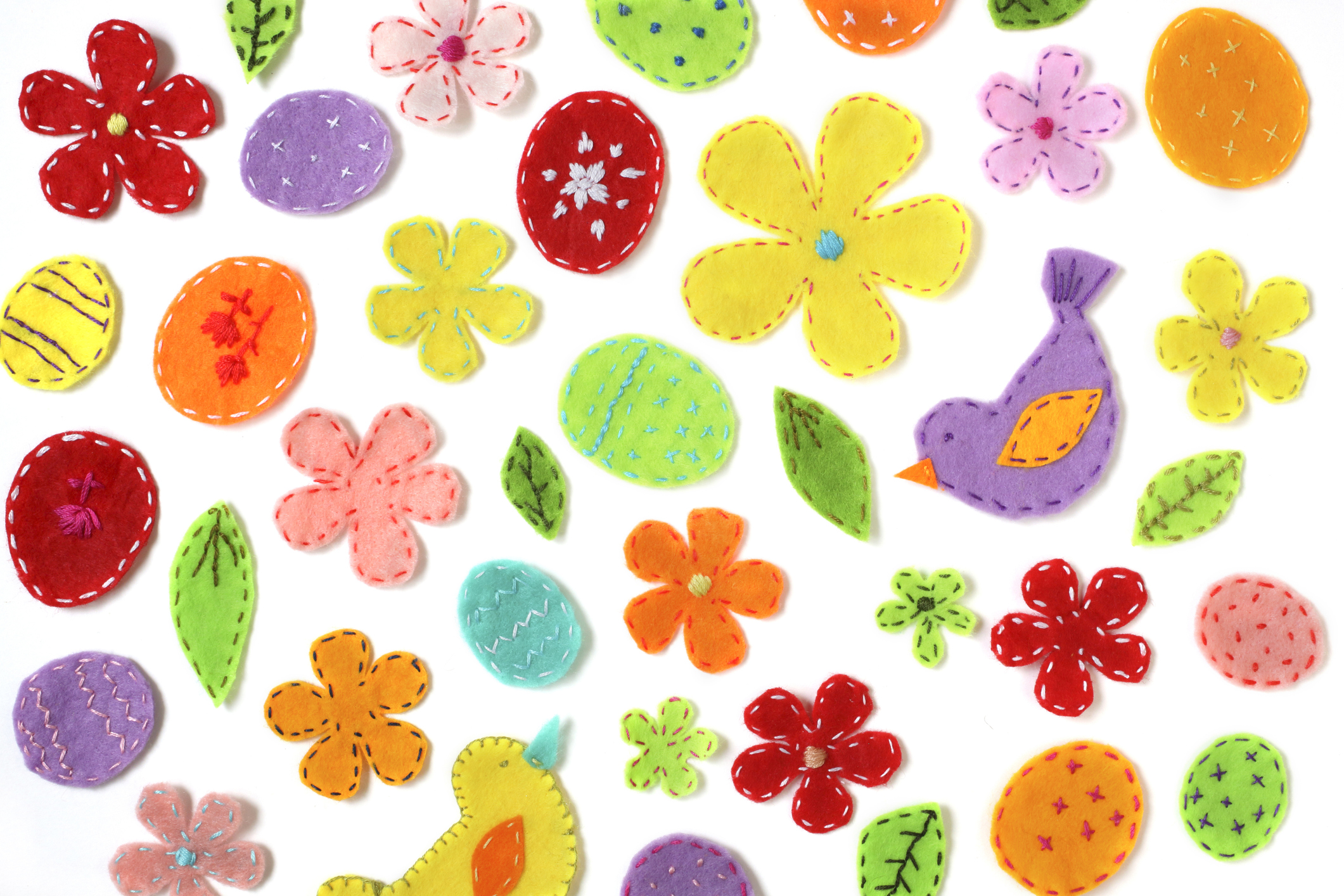 A range of felt shapes and animals decorated with cross-stitch.