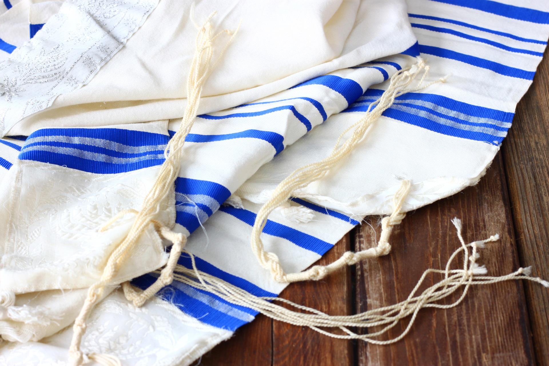 Close-up of a Jewish tallit (prayer shawl) with blue stripes and tzitzit (fringes).