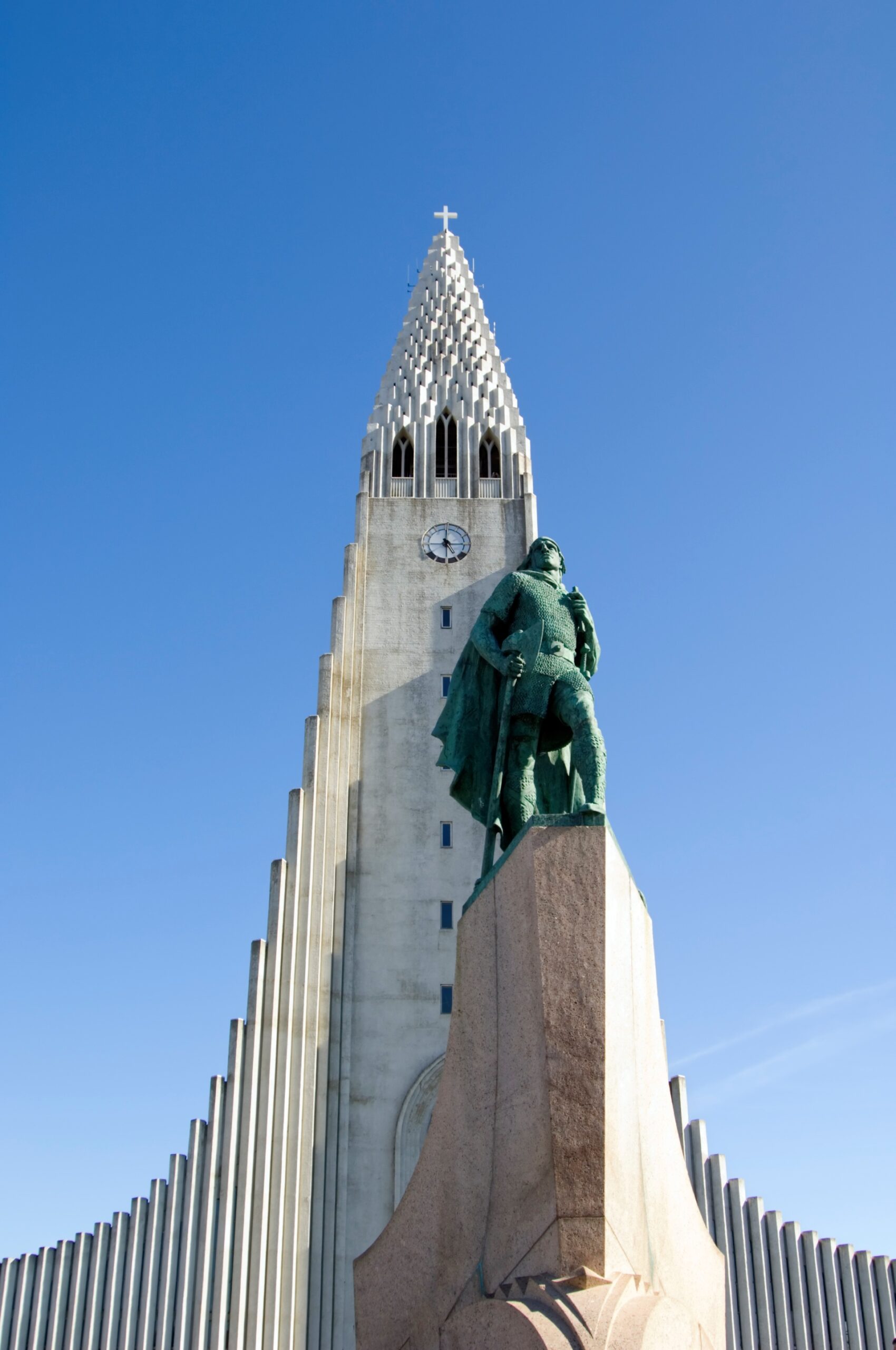 Statue of Leif Erikson in front of Hallgrímskirkja, a towering church in Reykjavik, Iceland, against a clear blue sky.
