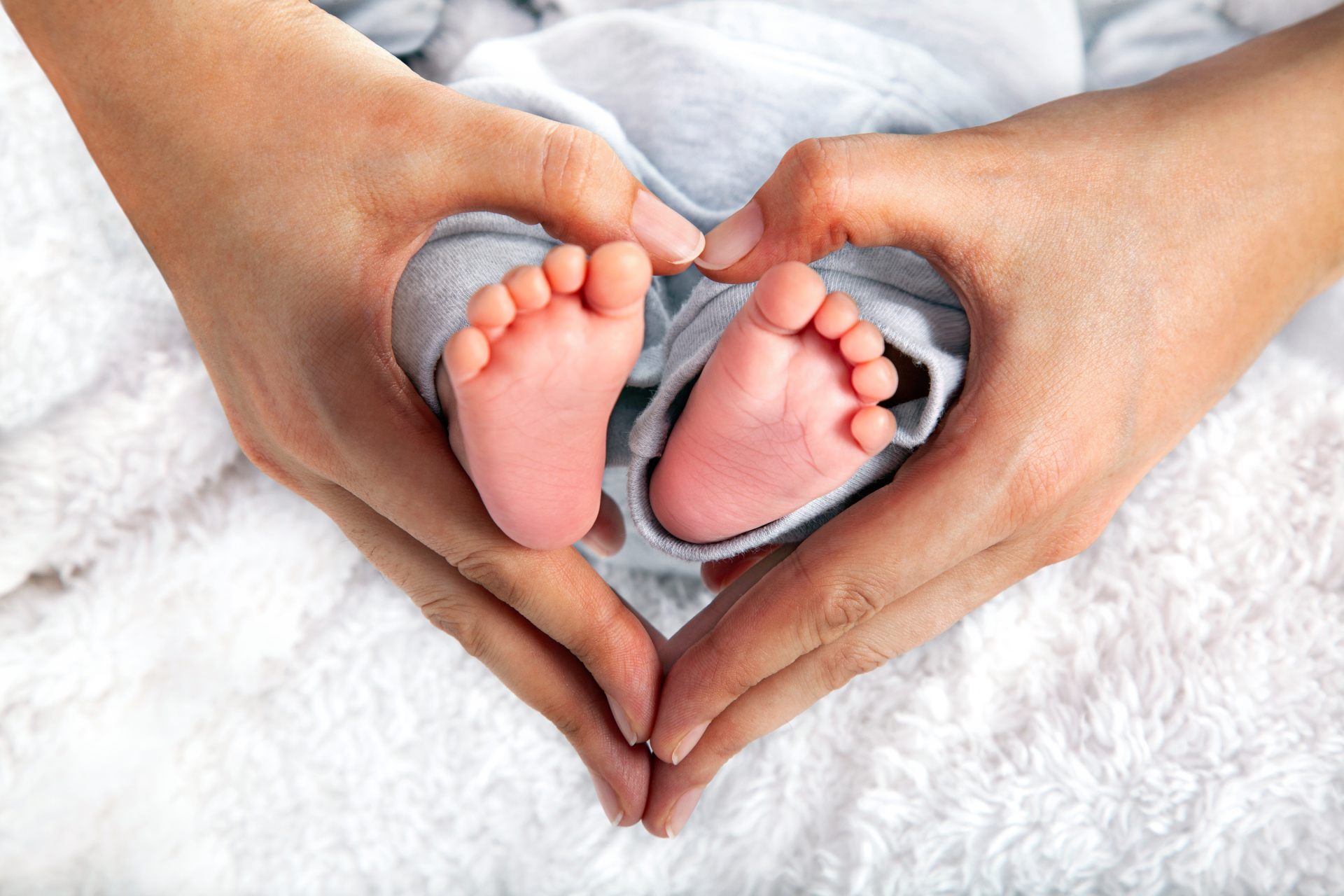 Baby feet held in hands forming a heart shape