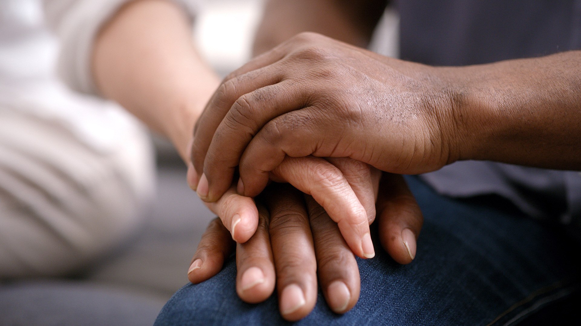 Close-up of two people holding hands in a comforting gesture