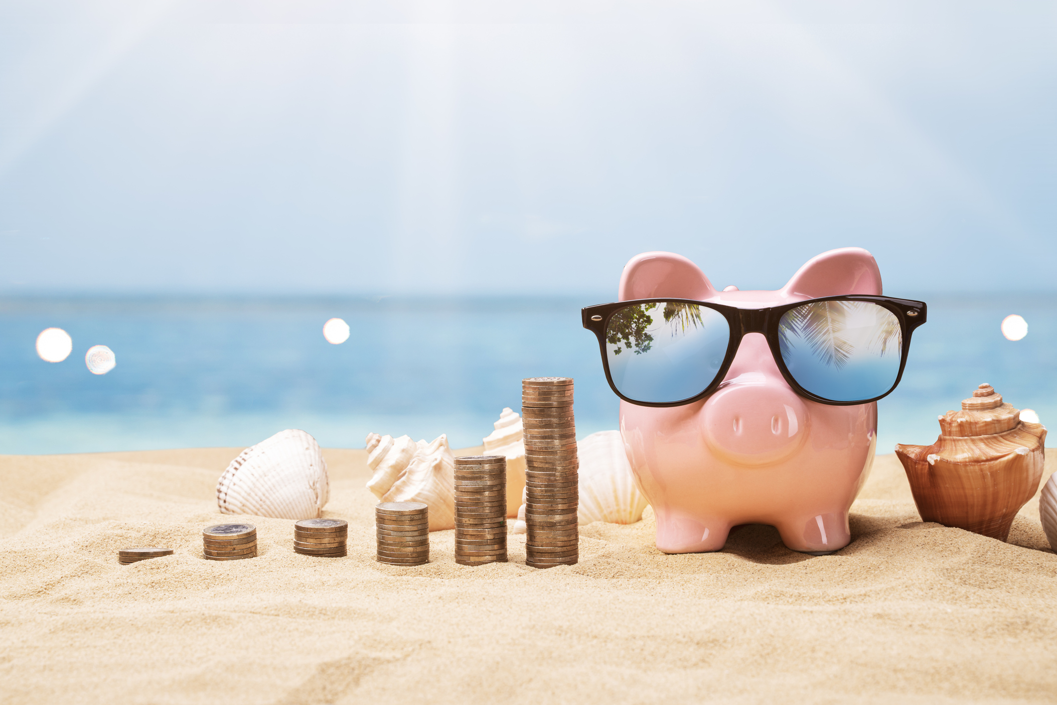 Piggy bank wearing sunglasses alongside stacked coins
