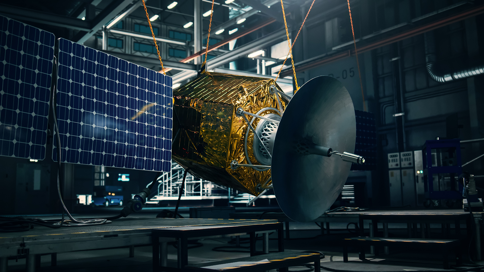 A satellite with blue solar panels and gold reflective material around the centre, hangs in a warehouse