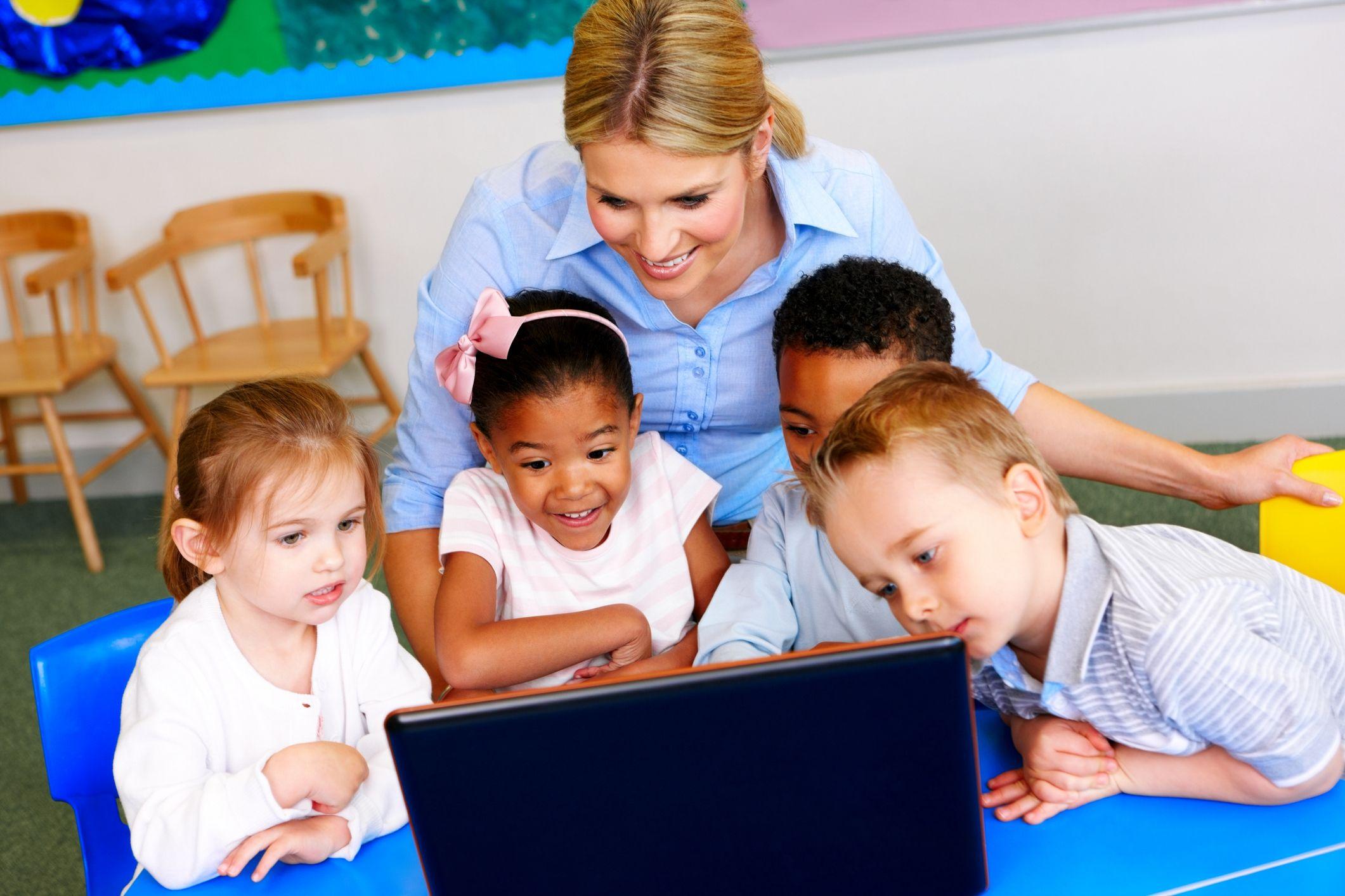 Young children with computer and teacher