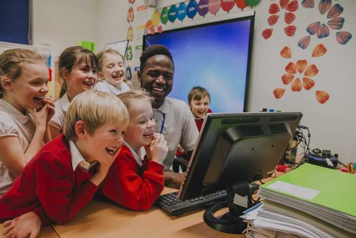 children standing around a seated teacher
