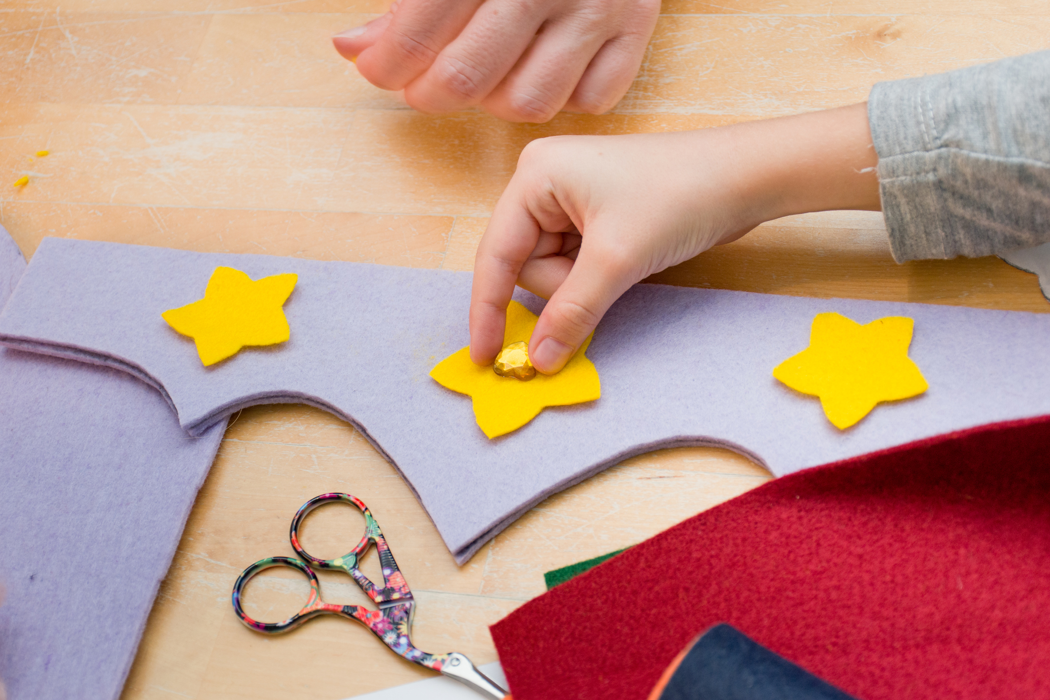 Child embellishing fabric with sequins and appliqué shapes.
