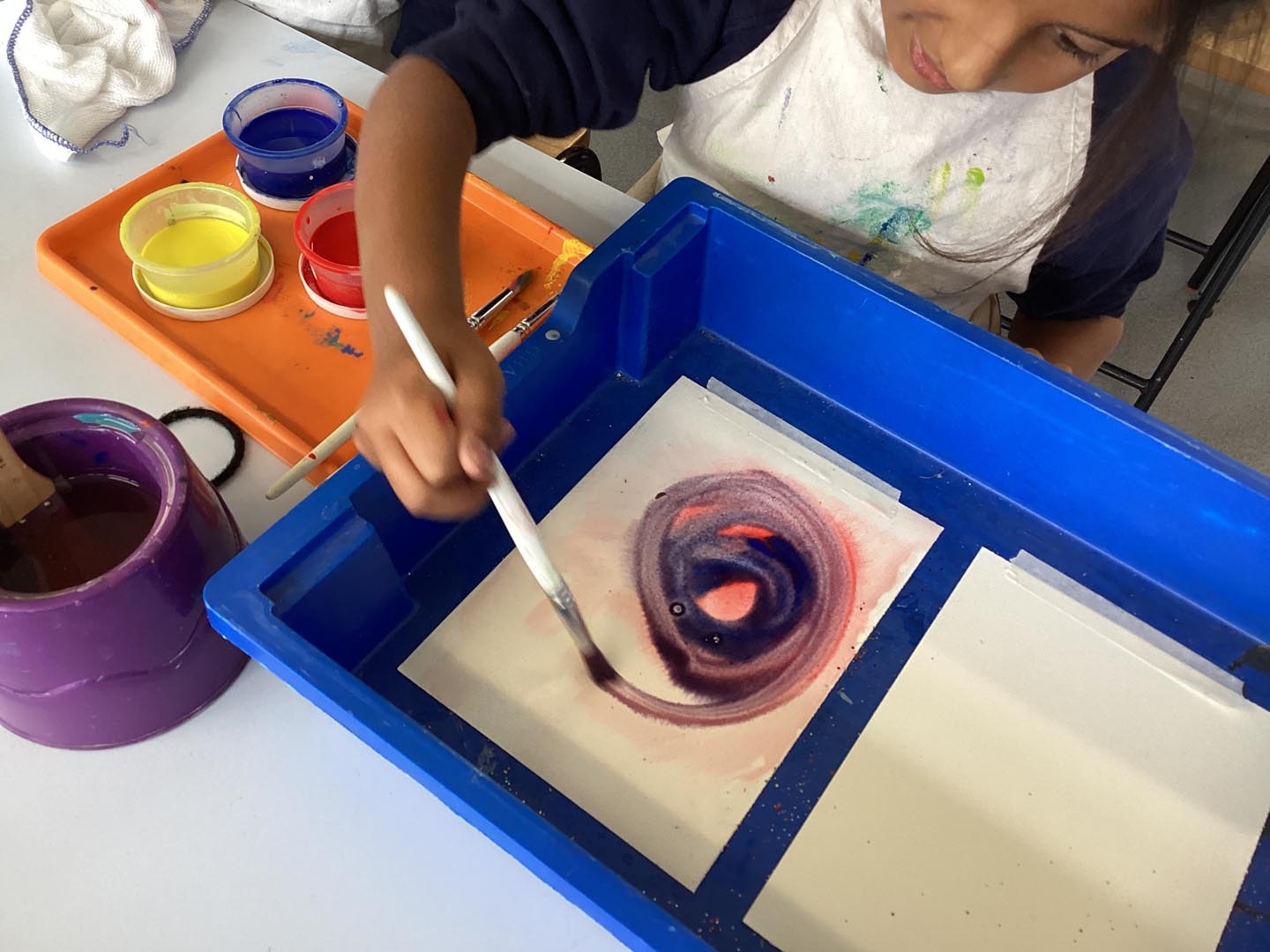 Children exploring mixing paint to make new colours in a tray