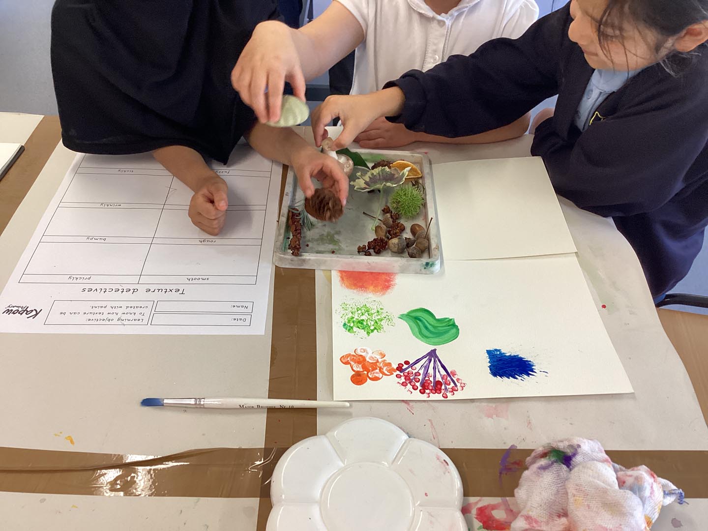 Children experimenting with creating textures using paints and tools