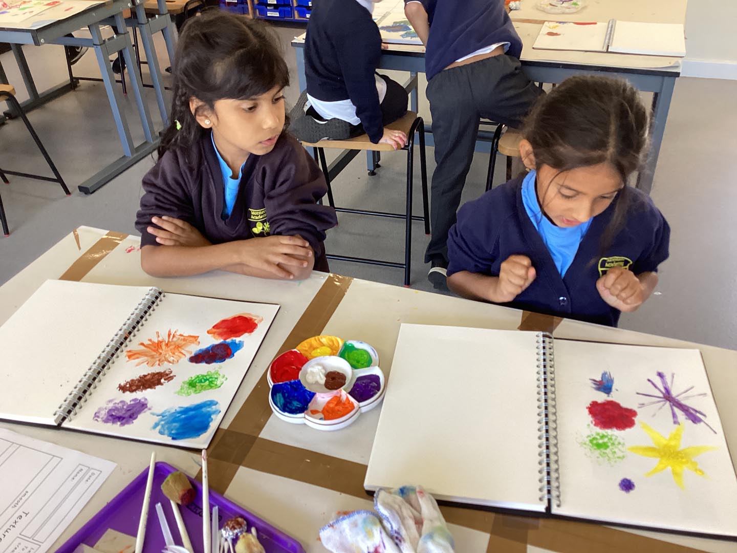 Children looking at their painted art work on books