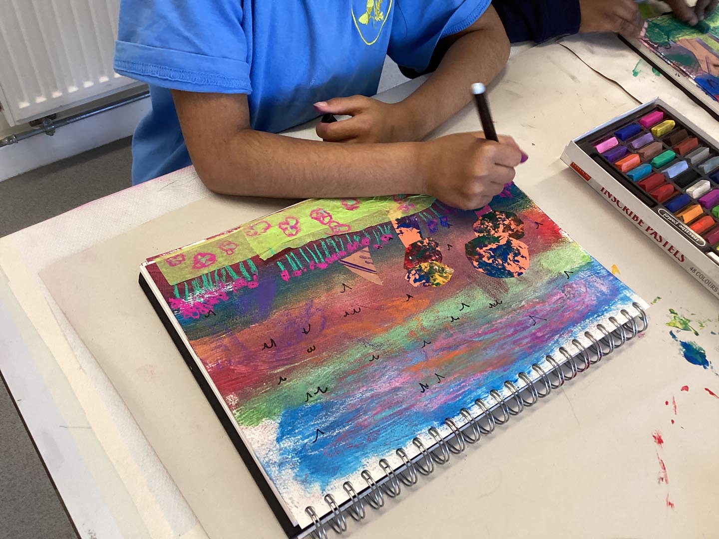 Child creating a collage on a colourful painted background