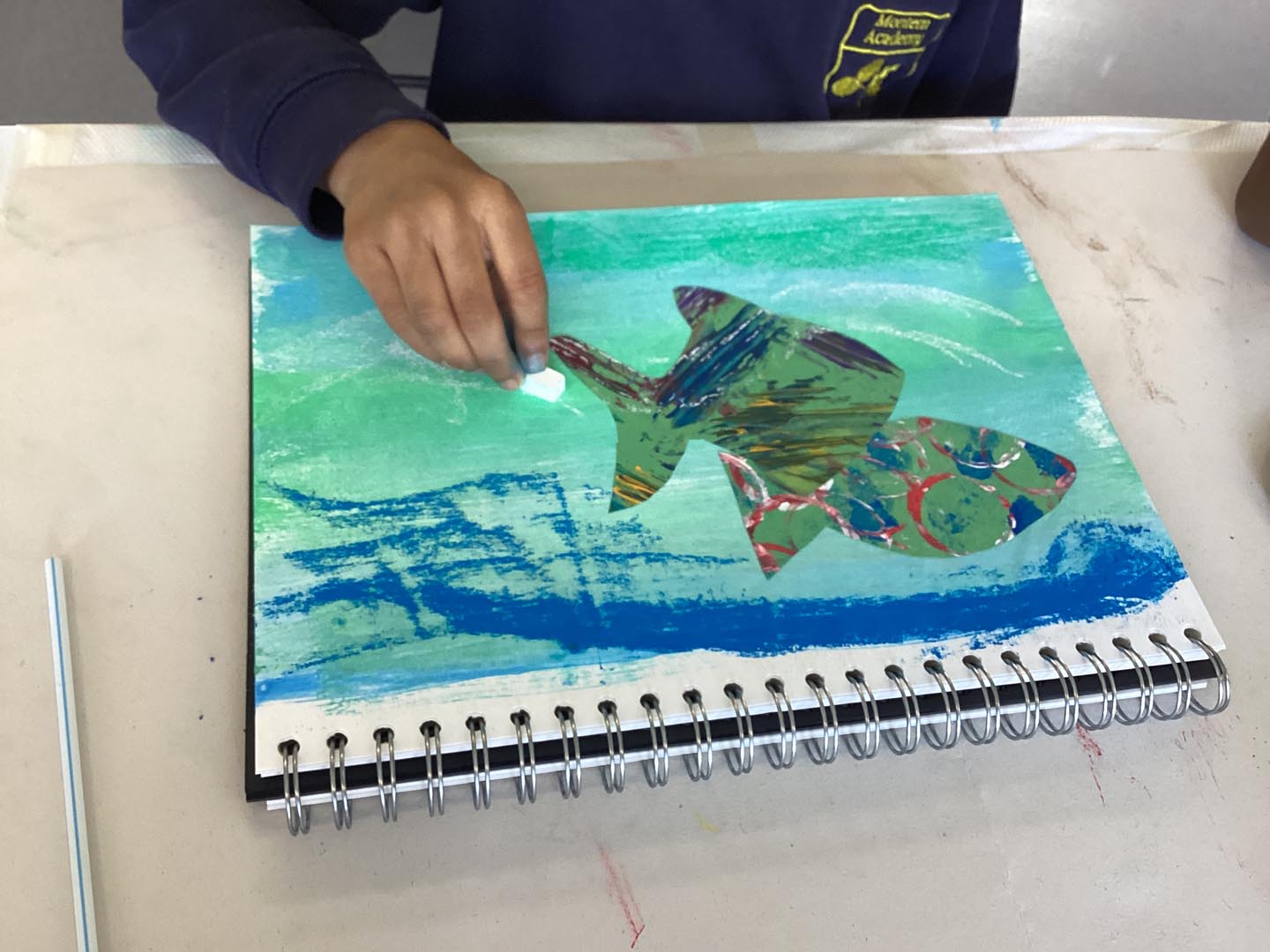 Child creating a collage on a colourful painted background