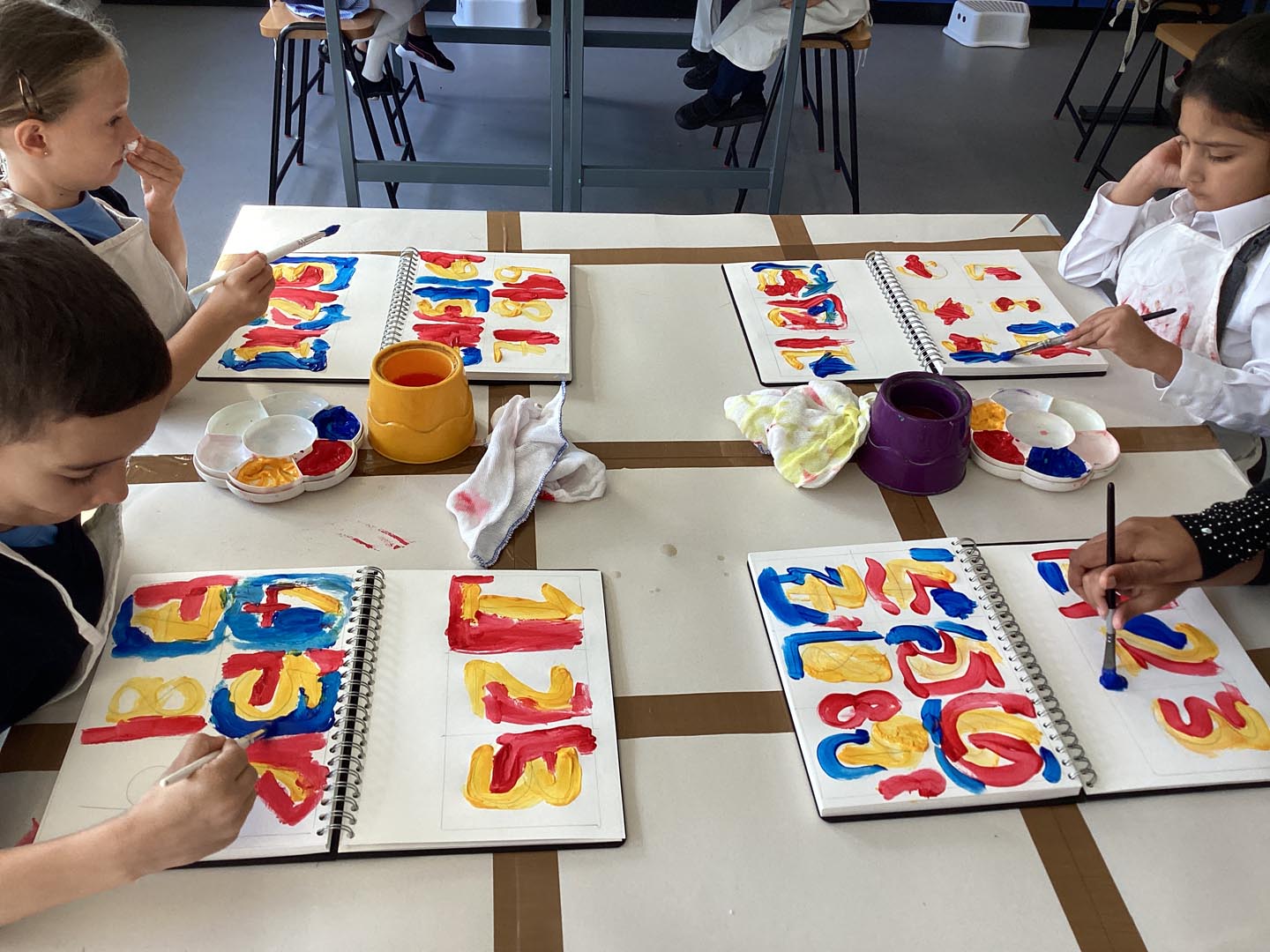 Group of school children painting with primary colours