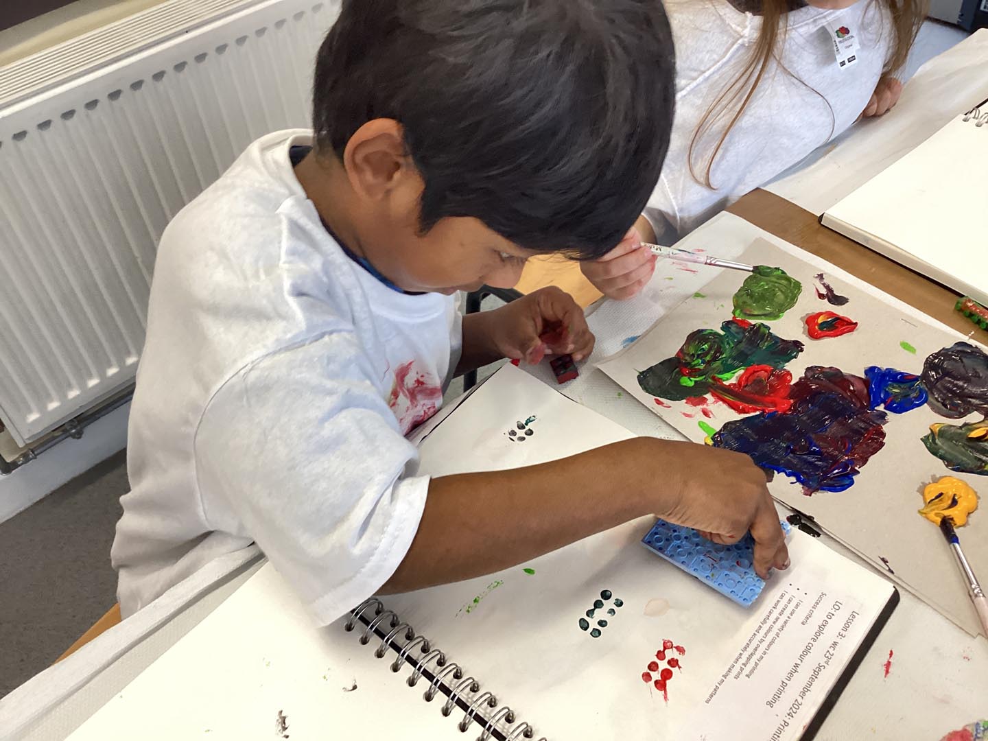 Child printing with building bricks and paint